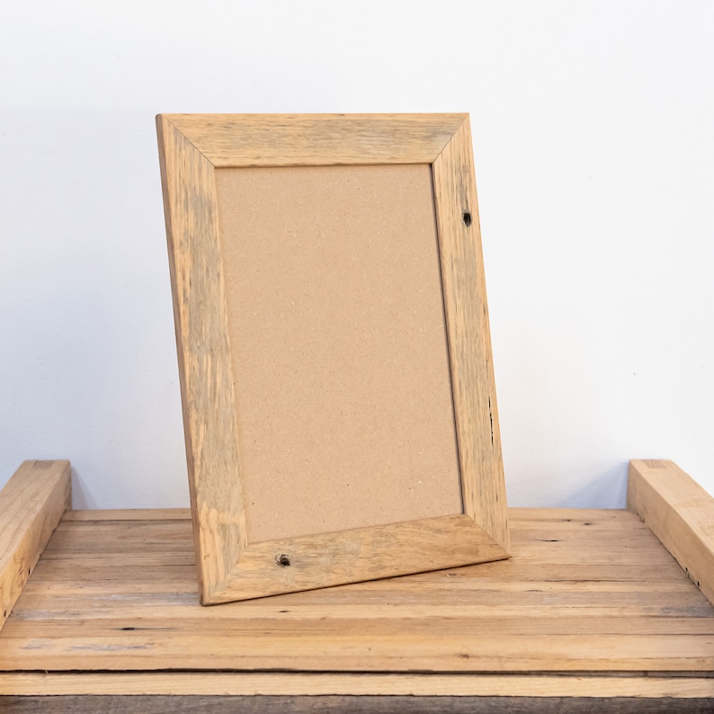 May include: A rustic wooden picture frame with a natural wood finish. The frame is made of reclaimed wood and has a distressed look. The frame is empty and ready to be filled with a photo or artwork.