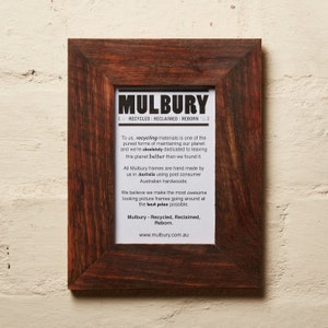May include: A brown wooden picture frame with a white mat and a printed message about recycled materials. The text reads "Mulbury - Recycled, Reclaimed, Reborn." and "www.mulbury.com.au".