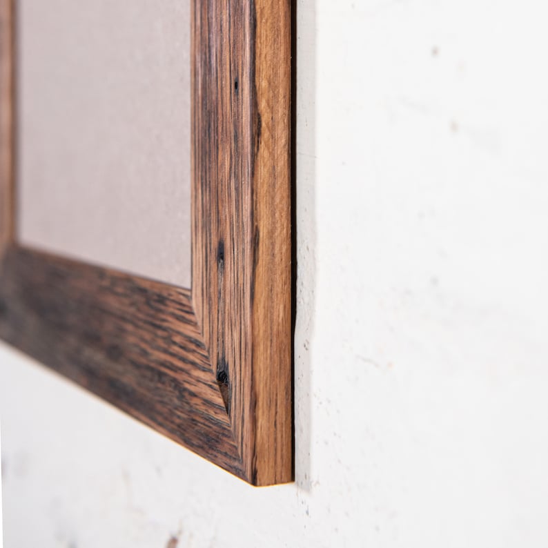 May include: Close-up of a wooden picture frame with a dark brown stain. The frame has a rustic look with visible wood grain and knots.