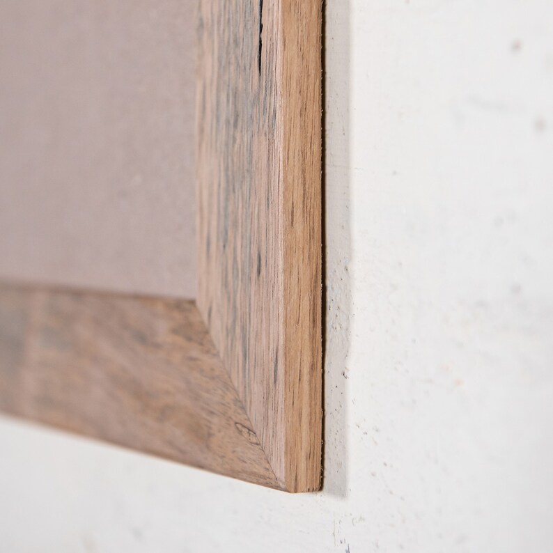 May include: Close-up of the corner of a wooden picture frame. The frame is made of reclaimed wood with a natural finish. The wood has a rustic look with knots and grain patterns.