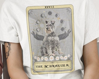 Puede incluir: Camiseta blanca con un gráfico de una carta de tarot con un perro schnauzer miniatura gris y blanco. La carta está etiquetada como "XXVII THE SCHNAUZER".