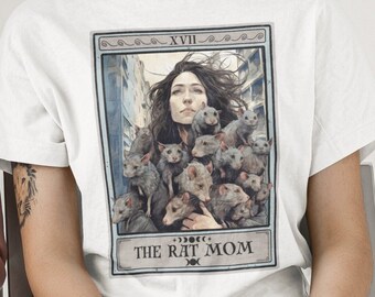 May include: White t-shirt with a graphic of a tarot card featuring a woman with a group of rats. The card is labeled "XVII The Rat Mom".