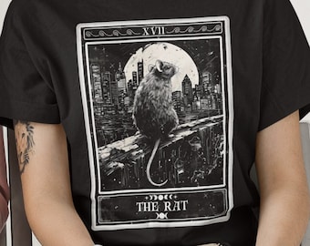 May include: Black t-shirt with a graphic of a tarot card depicting a rat sitting on a ledge in front of a city skyline. The card is labeled "XVIII THE RAT".