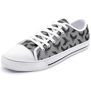 May include: Gray canvas low-top sneakers with a black bat pattern. The bats have red eyes.