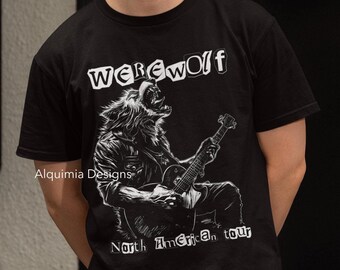 May include: Black t-shirt with a white graphic of a werewolf playing a guitar. The text "WEREWOLF" is above the werewolf and "North American Tour" is below. The text "Alquimia Designs" is in the lower left corner.