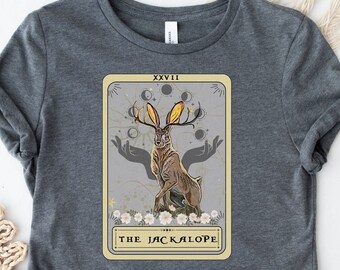 May include: Gray t-shirt with a graphic of a tarot card featuring a Jackalope with antlers and the text "XXVII THE JACKALOPE".