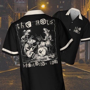 May include: Black button-up shirt with white trim and a white collar. The back features a graphic of rats playing instruments with the text "the rats" and "infestation tour". The shirt is displayed with a second shirt in the background.