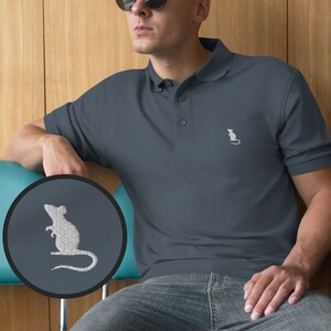 May include: A dark blue polo shirt with a white embroidered mouse on the right chest. The shirt is worn by a person wearing sunglasses.