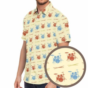 Puede incluir: Una camisa de botones de manga corta amarilla con un patrón repetido de baterías rojas y azules y baquetas.