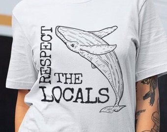 May include: White t-shirt with a black graphic of a whale and the text "Respect the Locals".