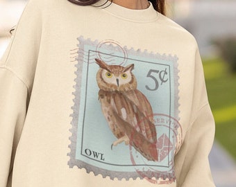 May include: A cream colored sweatshirt with a vintage-style stamp design featuring an owl and the text "5¢ OWL".