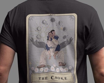 May include: Black t-shirt with a tarot card design featuring two figures in a chokehold pose. The card is titled "The Choke" and has a moon and star motif.