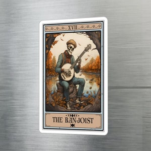 May include: A tarot card illustration depicting a skeleton playing a banjo in a forest setting. The card is titled "The Banjoist" and features a crescent moon symbol.