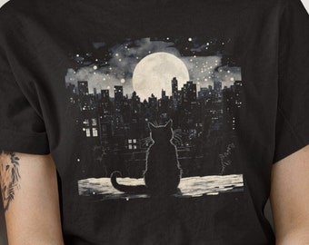 May include: Black t-shirt with a graphic of a black cat sitting on a rooftop overlooking a city skyline with a full moon in the background.