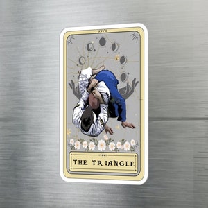 Puede incluir: Una ilustración de carta de tarot que representa un movimiento de jiu-jitsu llamado "The Triangle". La carta es beige con detalles dorados y presenta un kimono blanco y azul, un fondo blanco y un diseño floral en la parte inferior.