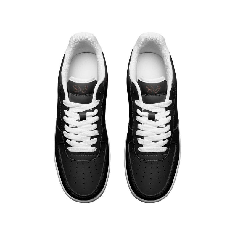May include: A pair of black leather sneakers with white laces and a white sole. The sneakers have a small brown logo on the side that says "B+J".