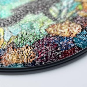 Op de afbeelding: Een ronde, zwarte dienblad met een kleurrijk moza&iuml;ekontwerp. De moza&iuml;ek is gemaakt van kleine, onregelmatige stukjes glas in tinten groen, blauw, paars, oranje en geel. De dienblad heeft een zwarte rand.