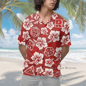 May include: Red short-sleeved button-up shirt with a white hibiscus flower and dice pattern. The shirt has the text "Alquimia Designs" on the bottom right corner.