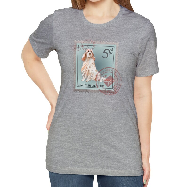 Op de afbeelding: Grijze t-shirt met een postzegelontwerp met een illustratie van een Engelse Setter. De postzegel heeft een blauwgroene achtergrond, het nummer "5&cent;" en de woorden "English Setter" en "Postal Service".