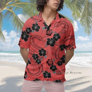 Puede incluir: Una camisa roja de manga corta con botones con un estampado de serpiente negra y blanca y flores. La camisa tiene cuello y cierre de botones.