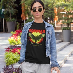 May include: Black t-shirt with a graphic of a mothman, a large winged creature with glowing red eyes, against a yellow moon and red sky. The text "Mothman" is in red and "Point Pleasant, WV" is in white.