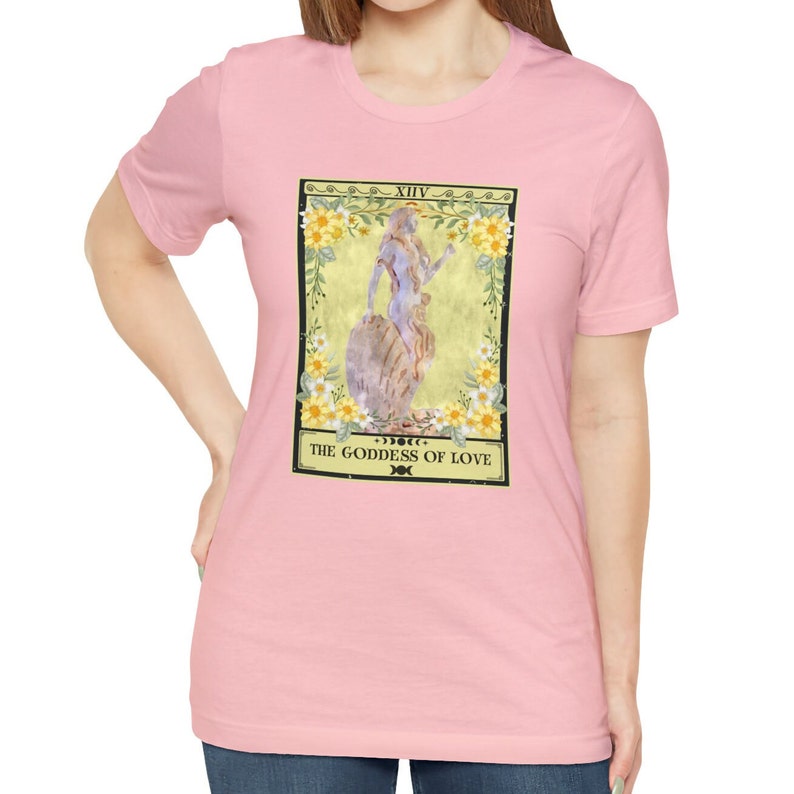 May include: Pink t-shirt with a graphic of a tarot card depicting a woman with flowers and the text "XIV THE GODDESS OF LOVE"