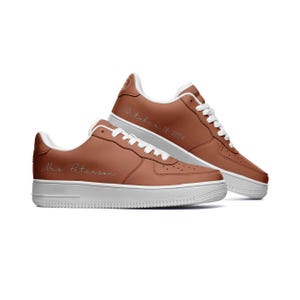 May include: A pair of brown leather sneakers with white soles. The left shoe has the text "Mrs. Peterson" on the side, and the right shoe has the text "October 18, 2024" on the side.