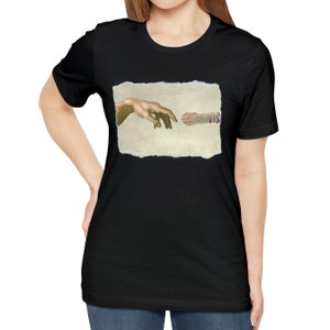 May include: A black t-shirt with a graphic of a hand and a cat paw reaching towards each other, inspired by Michelangelo's The Creation of Adam.