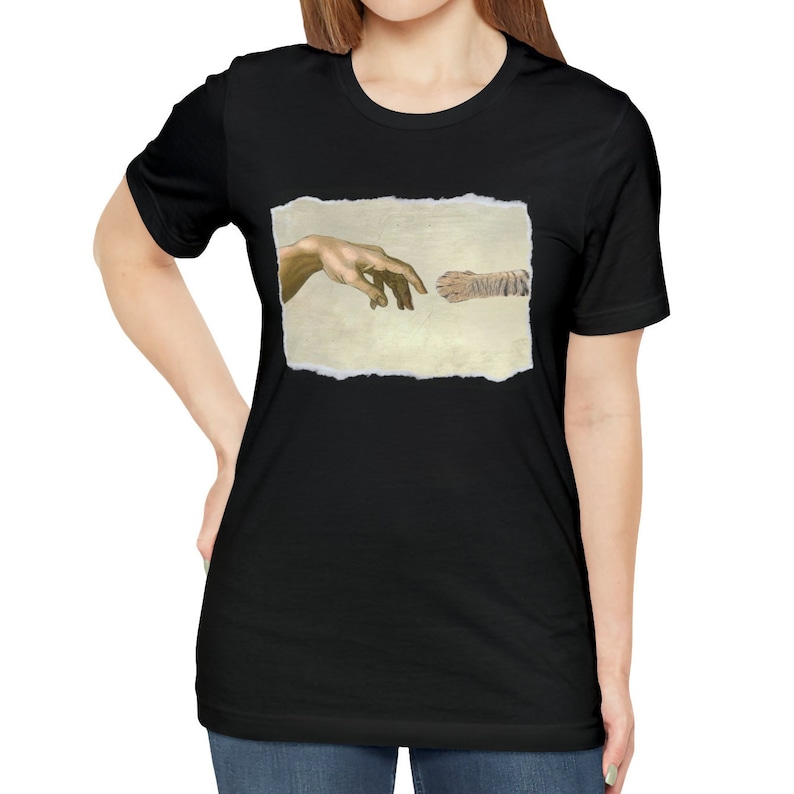 May include: A black t-shirt with a graphic of a hand and a cat paw reaching towards each other, inspired by Michelangelo's The Creation of Adam.