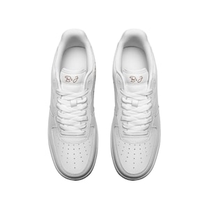May include: A pair of white leather low-top sneakers with a pink "B&J" logo on each shoe.