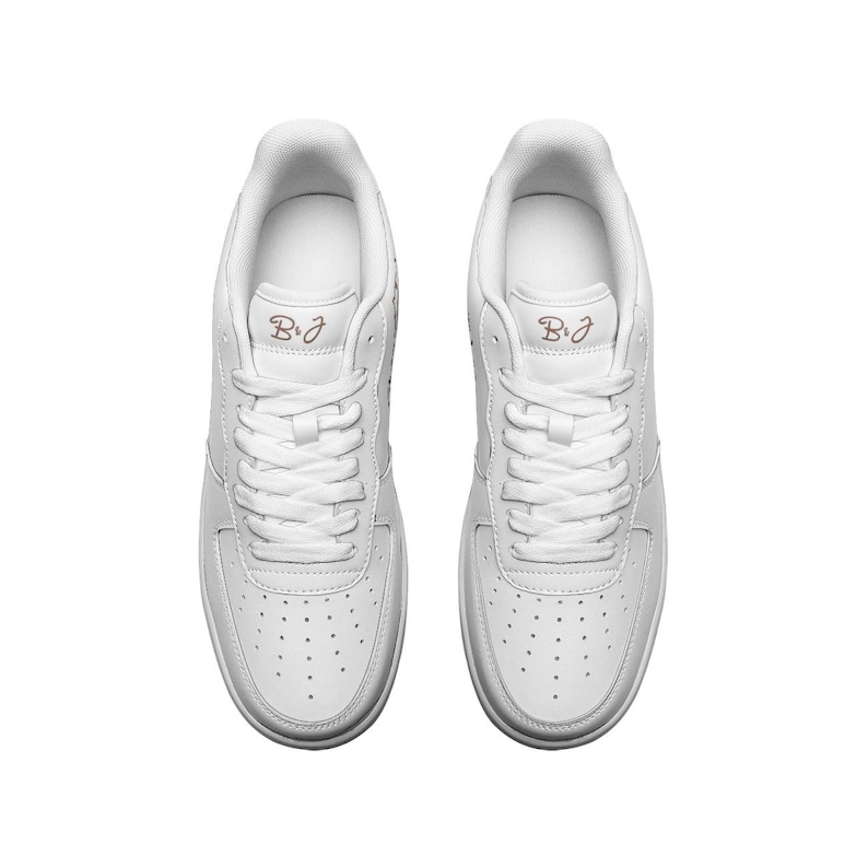 May include: A pair of white leather low-top sneakers with a pink "B&J" logo on each shoe.