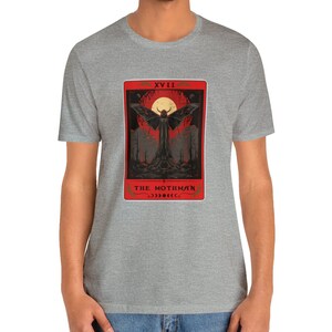 May include: A grey t-shirt featuring a red and black illustration of a mothman with the text "XVIII THE MOTHMAN" on the front.