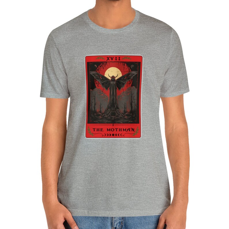 May include: A grey t-shirt featuring a red and black illustration of a mothman with the text "XVIII THE MOTHMAN" on the front.