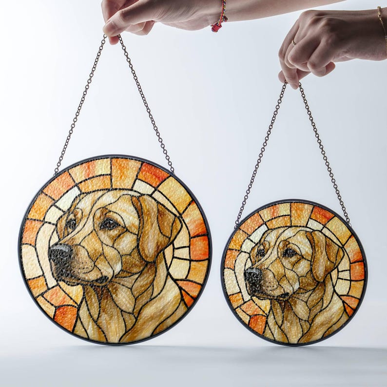 May include: Two round stained glass panels featuring a Labrador Retriever. The panels have a black metal frame and a chain for hanging. The dog's portrait is in shades of brown, tan, and orange, with a stained glass effect.