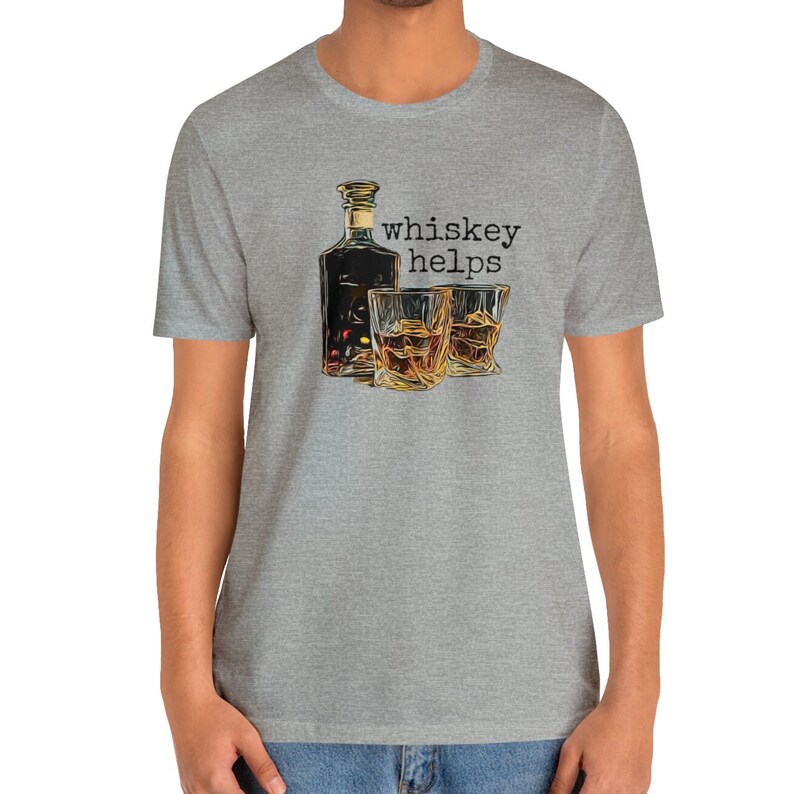 K&ouml;nnte beinhalten: Ein heidefarbenes T-Shirt mit einem Aufdruck einer Flasche Whiskey und zwei Gl&auml;sern. Der Text "whiskey helps" ist auf dem Shirt gedruckt.