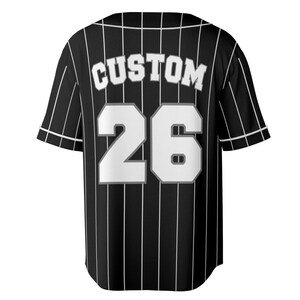 May include: Black and white baseball jersey with vertical white stripes. The word "CUSTOM" is arched across the upper back, above the number "26" in white. The jersey has short sleeves and a button-up front.