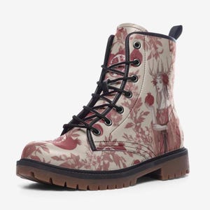 Może przedstawiać: Kremowe buty bojowe z czerwonym kwiatowym i granatowym wzorem. Buty mają kobietę trzymającą granat. Czarne sznurowadła i brązowa podeszwa dopełniają całości.