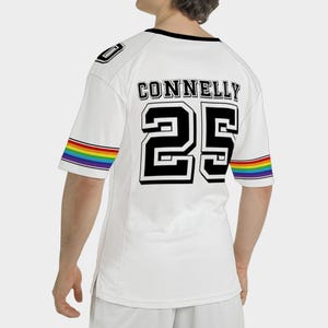 Puede incluir: Camiseta blanca con el nombre "CONNELLEY" y el n&uacute;mero "25" en letras negras. Las mangas tienen rayas de arco&iacute;ris. La camiseta tiene cuello negro y ribete negro en los hombros.