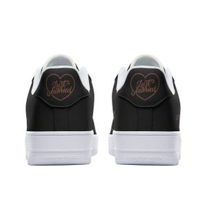 May include: A pair of black sneakers with white soles. The back of each shoe has a heart with the text "Just Married" in a copper color.