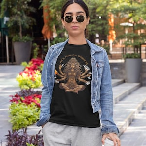 May include: A black t-shirt with a graphic of a woman with multiple arms holding various bar tending tools. The text "Bar Tending Goddess" is written in a circle around the woman.