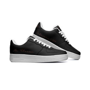 May include: A pair of black leather sneakers with white soles. The left shoe has the text "Mr. Peterson" written on the side in a cursive font. The right shoe has the text "February 3, 2024" written on the side in a cursive font.