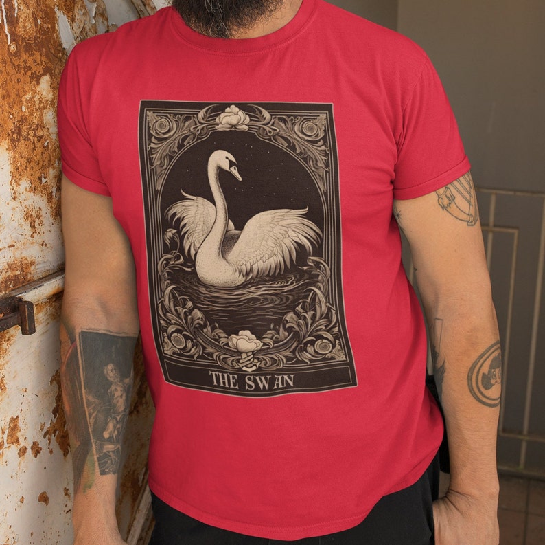 May include: Red t-shirt with a vintage illustration of a swan in a decorative frame. The text "THE SWAN" is printed below the image.