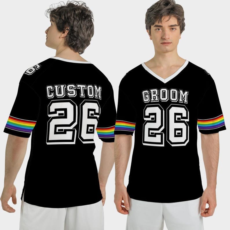 Puede incluir: Camiseta negra estilo jersey con ribete blanco y la palabra "GROOM" o "CUSTOM" en letras blancas. El n&uacute;mero "26" tambi&eacute;n es blanco. Las mangas tienen una franja arco&iacute;ris. La camiseta tiene cuello en V.