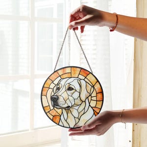 May include: Round stained glass window art featuring a Labrador Retriever dog. The dog's portrait is in the center, surrounded by a circular design with shades of orange and yellow. A black chain is attached for hanging.