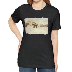 May include: A black t-shirt with a print of a cat paw and a human hand reaching out to touch it, referencing the famous "Creation of Adam" painting.