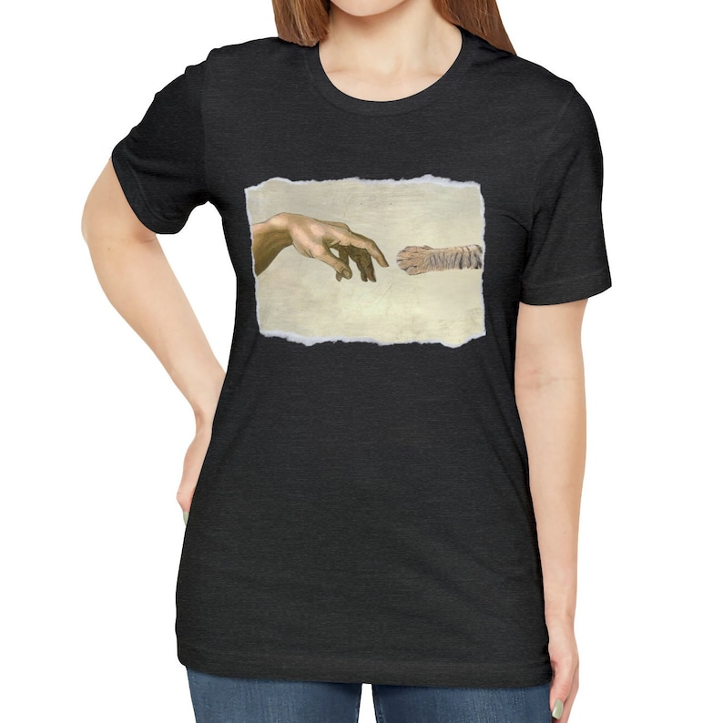 May include: A black t-shirt with a print of a cat paw and a human hand reaching out to touch it, referencing the famous "Creation of Adam" painting.