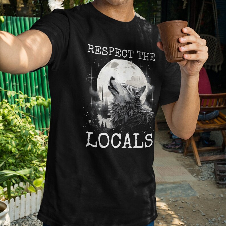 May include: Black t-shirt with a wolf howling at the moon graphic. The text "Respect the Locals" is printed on the shirt.