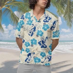 May include: A cream-colored short-sleeved button-up shirt with a blue and white floral pattern. The pattern features figures in a martial arts pose.