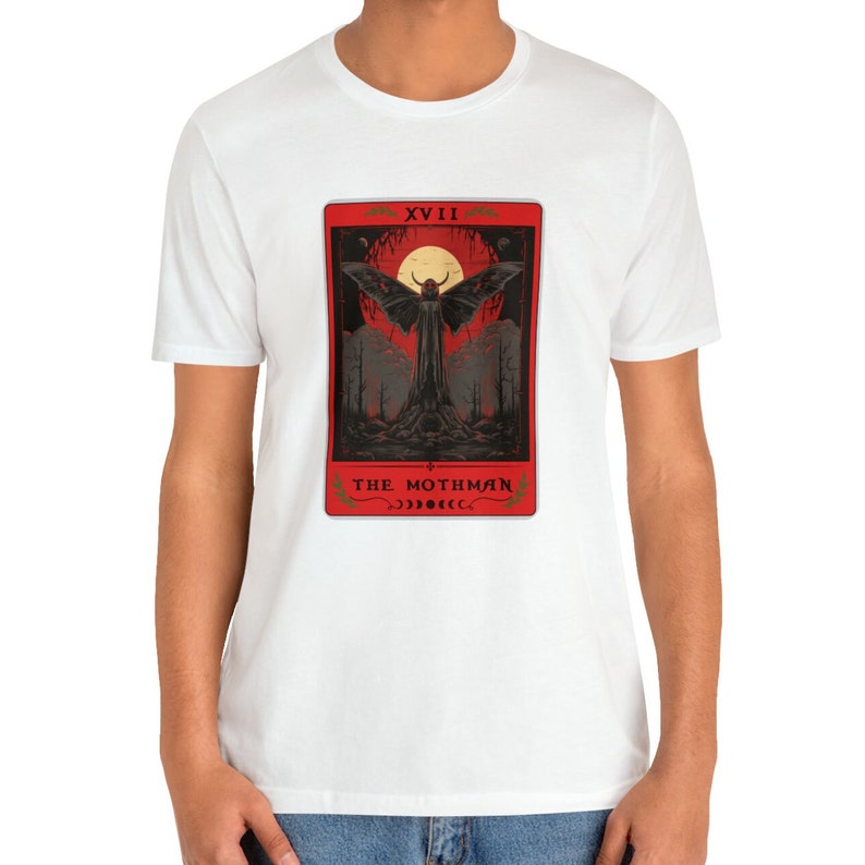 May include: White t-shirt featuring a red tarot card design with a black mothman figure and the text "XVIII THE MOTHMAN" on the card.