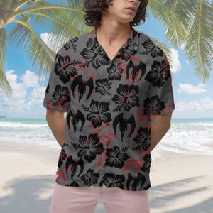 May include: A gray short-sleeved button-up shirt with a black and red floral pattern. The flowers have a dark red center and black petals. The shirt has a relaxed fit and a collar.